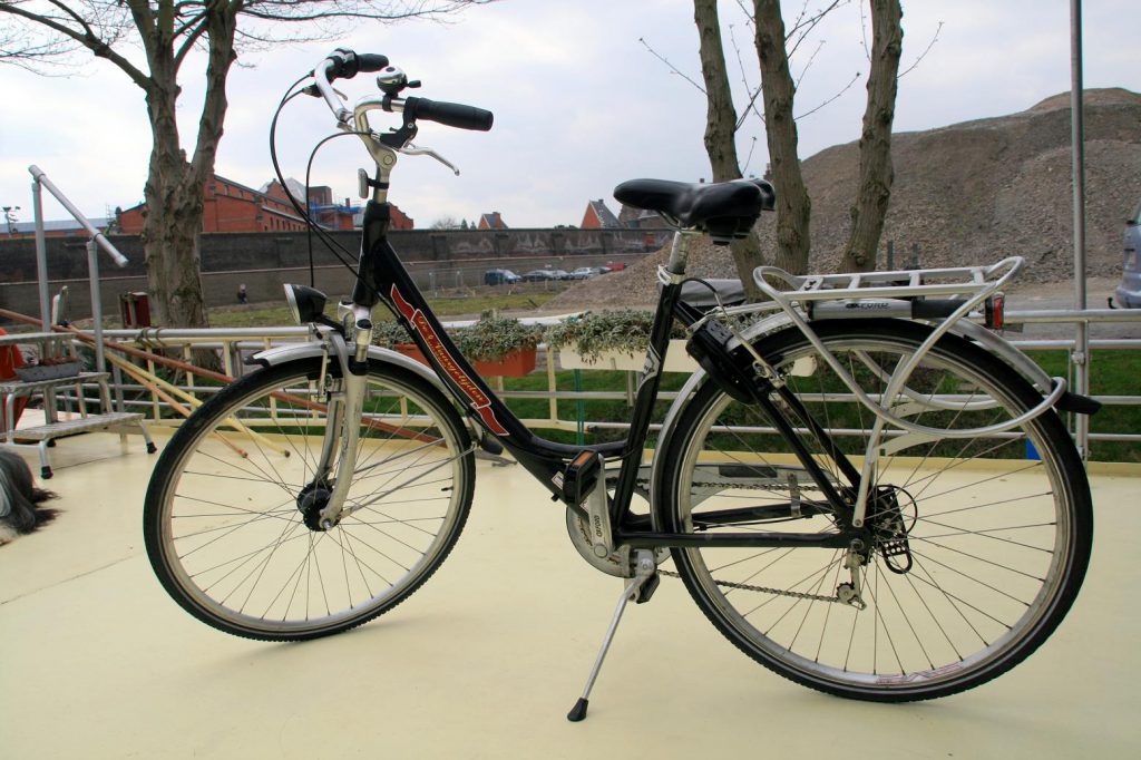 Schwarzes Stadtfahrrad mit Handbremsen und Fahrradschloss steht auf dem Sonnendeck.