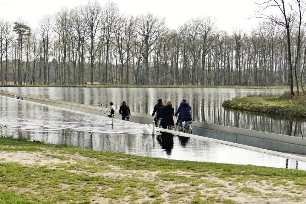 Fietsers rijden over een pad dwars door een meer in Limburg
